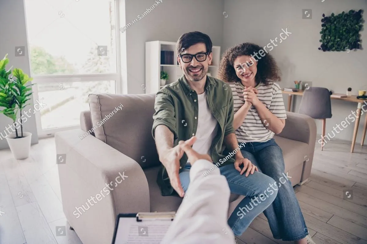 Smiling couple on a sofa, the man reaching to shake a therapist’s hand