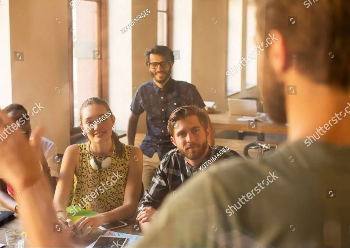 Colleagues around a table listening to a man speaking in a casual meeting