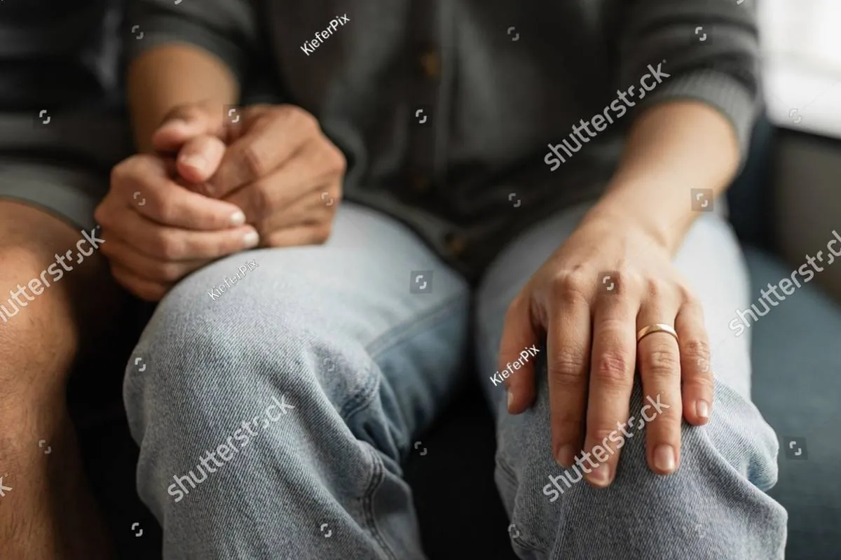 Close-up of a woman resting her hand on a man’s knee while seated together