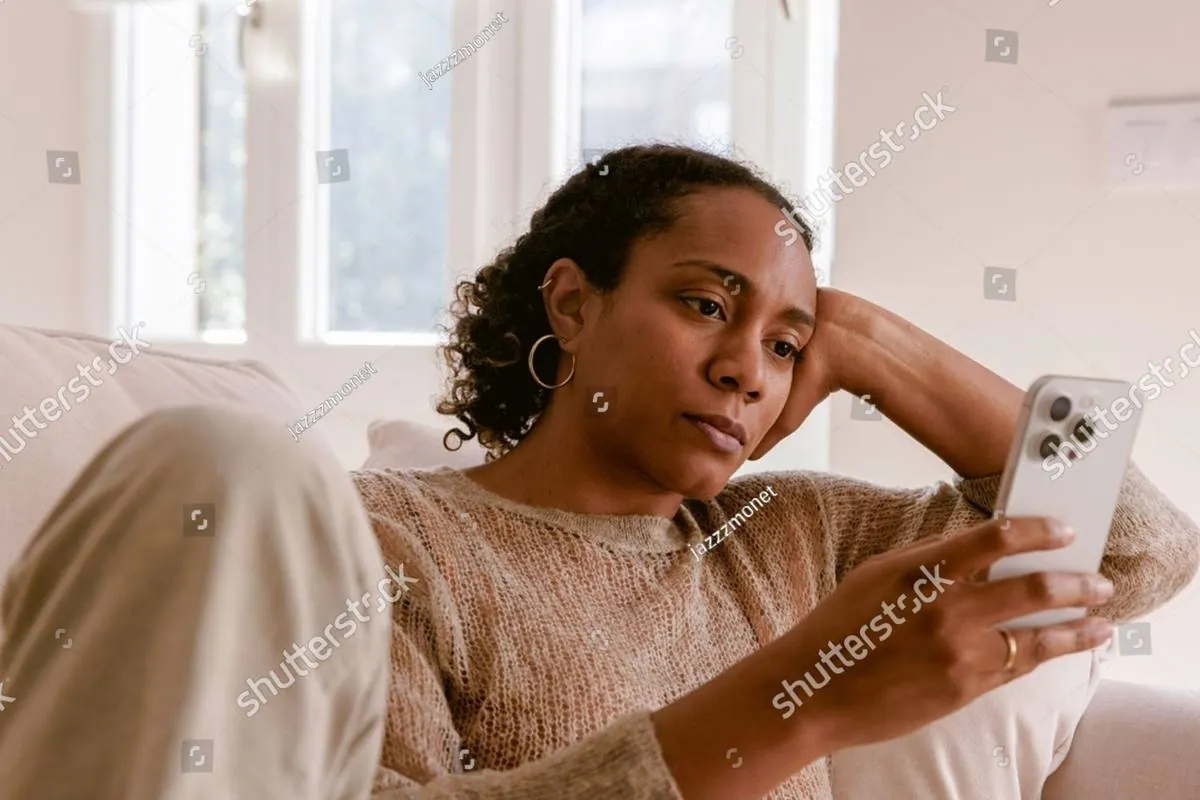 Woman resting her head on her hand while looking at her phone on a couch