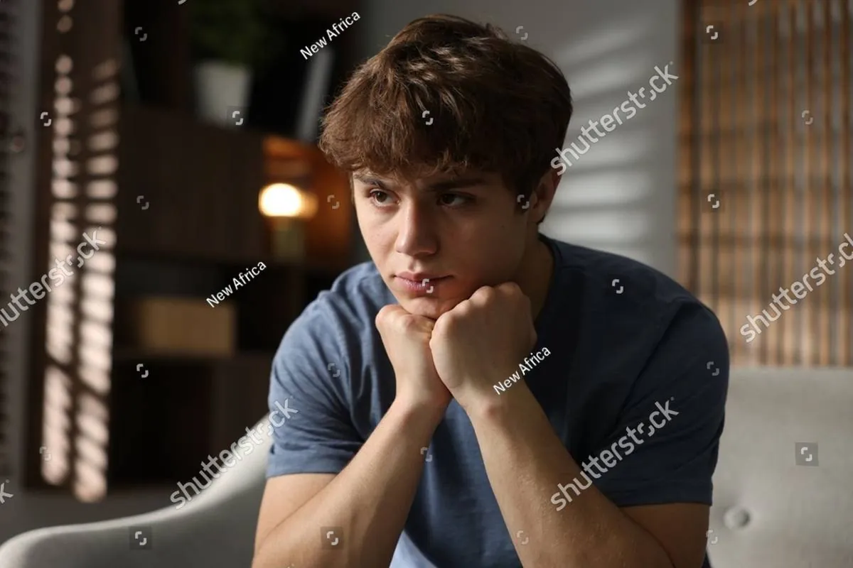 Teenage boy resting his chin on his fists, looking away pensively