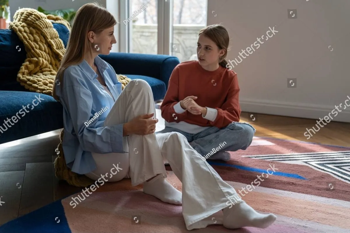 Mother and teenage daughter sitting on the living room floor talking