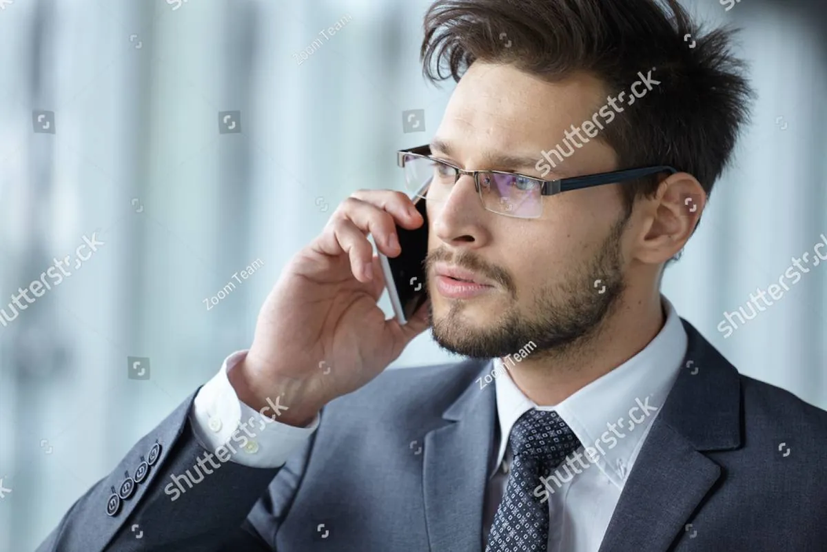 Man in a suit and glasses talking on his phone, looking serious