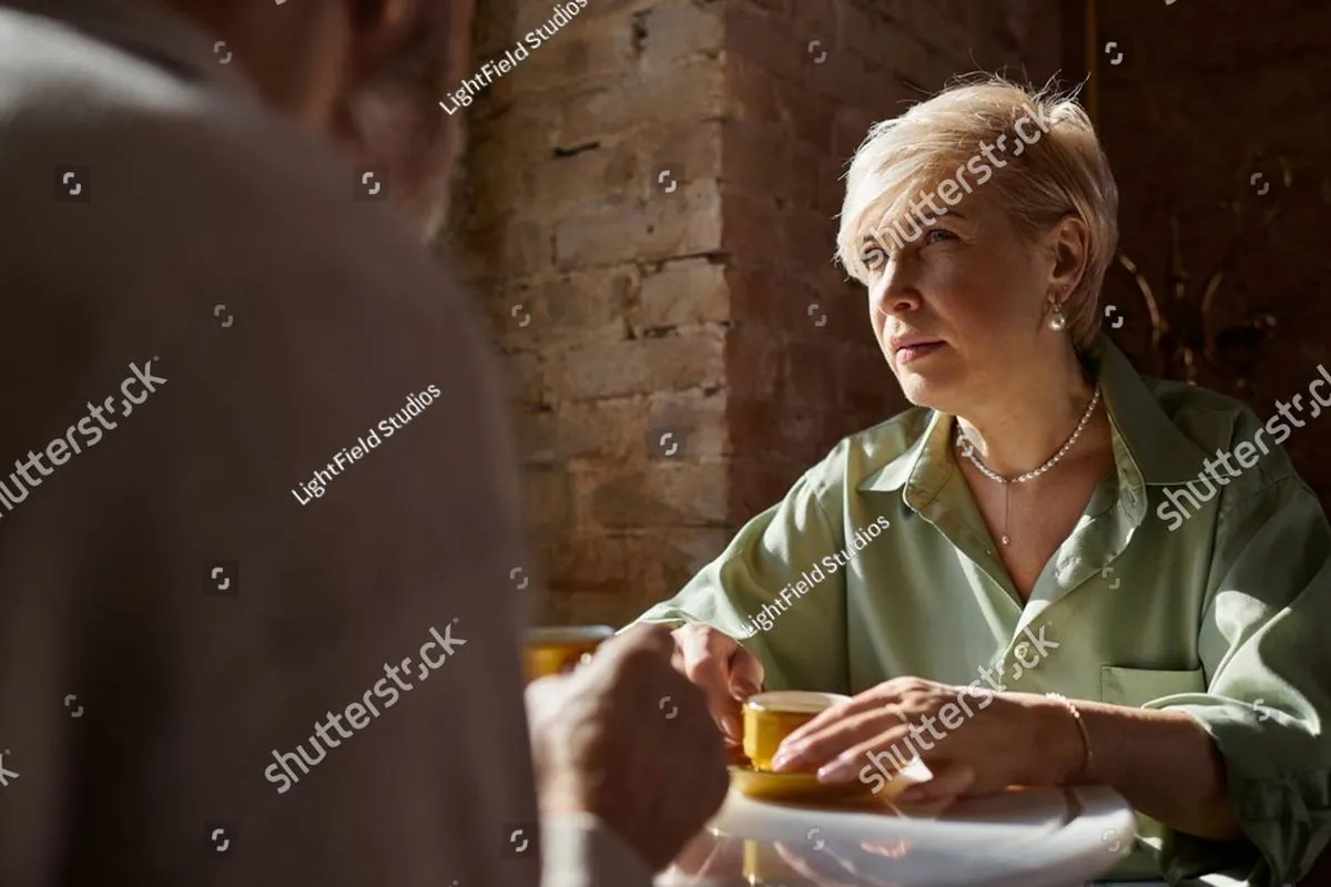 Blonde woman in a green blouse listening intently across a café table