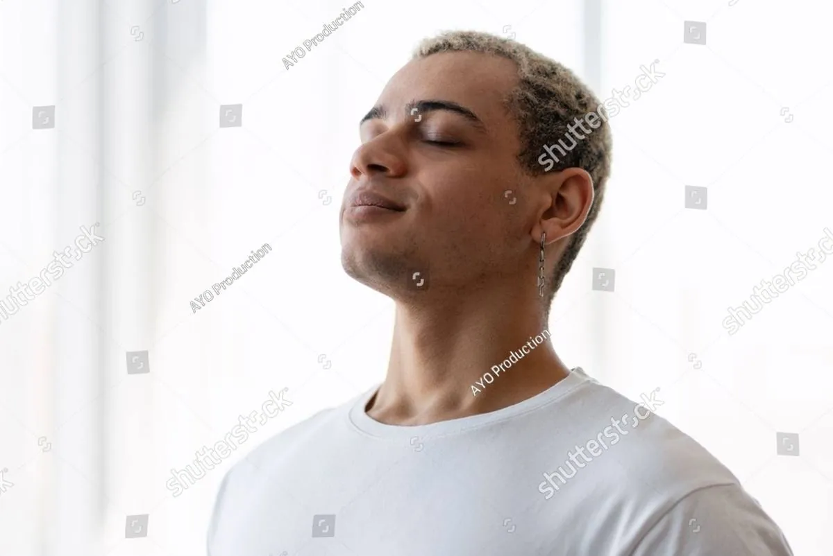 Young man in a white T-shirt with eyes closed, face lifted, breathing calmly
